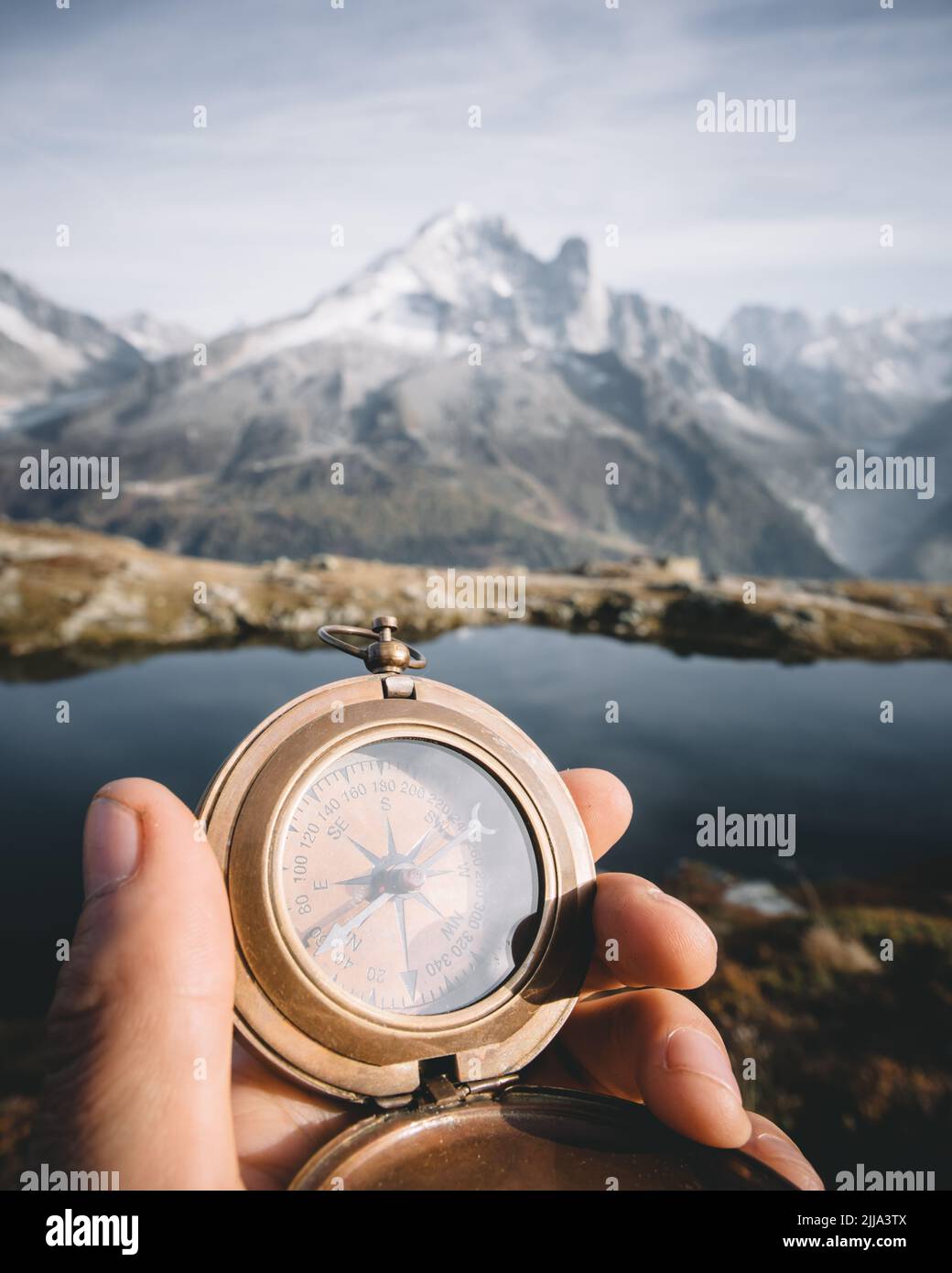 Man with compass in hand in high mountains near clear lake. Travel concept. Landscape photography Stock Photo