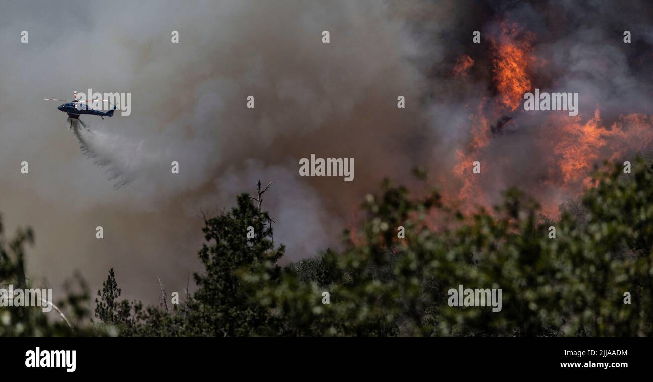 A firefighting helicopter drops water on a hillside to control the Oak Fire as it burns near Darrah in Mariposa County, California, U.S., July 24, 2022. REUTERS/Carlos Barria REFILE - QUALITY REPEAT Stock Photo