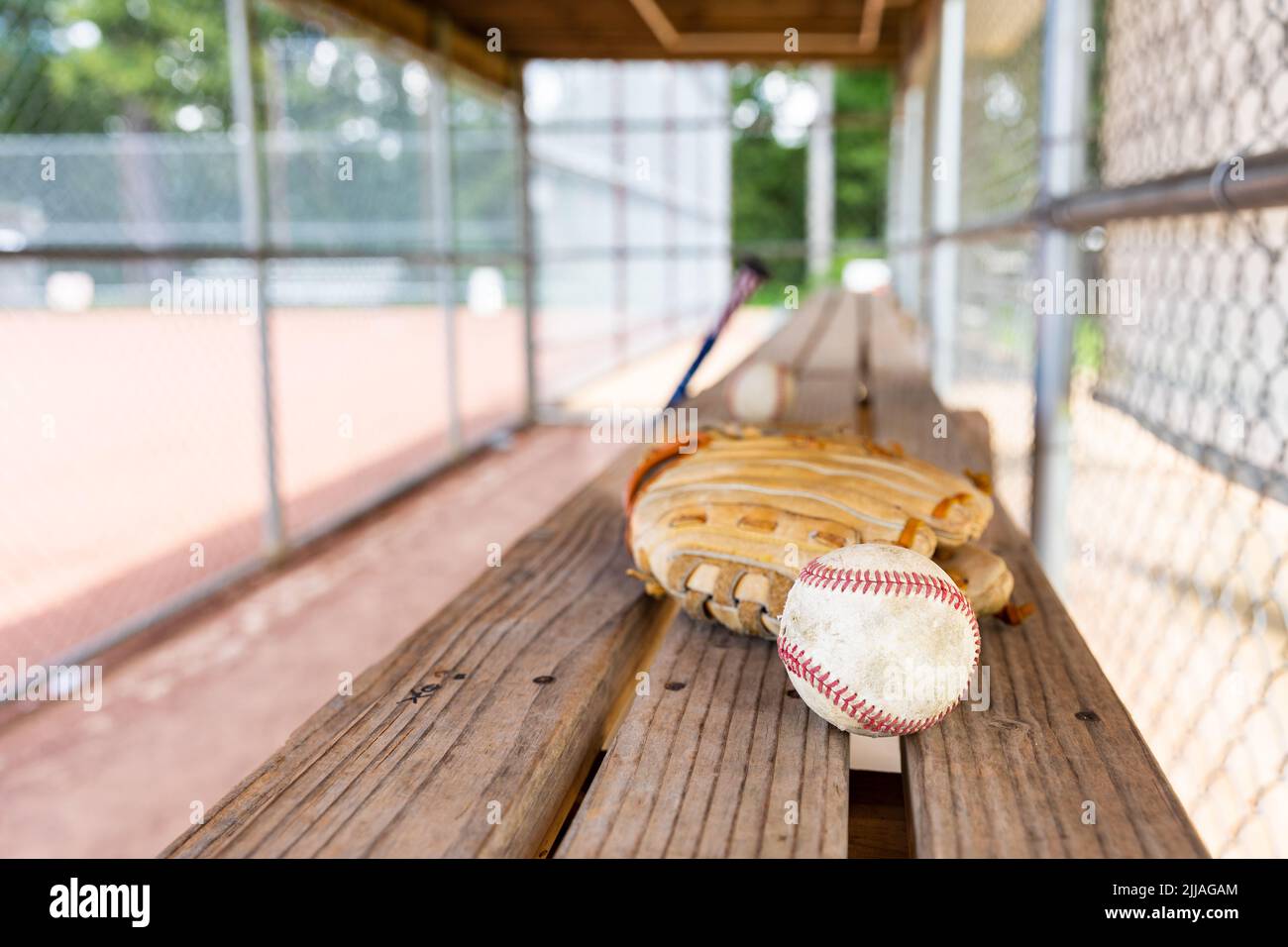 Baseball and glove on dugout bench with blurred background Stock Photo