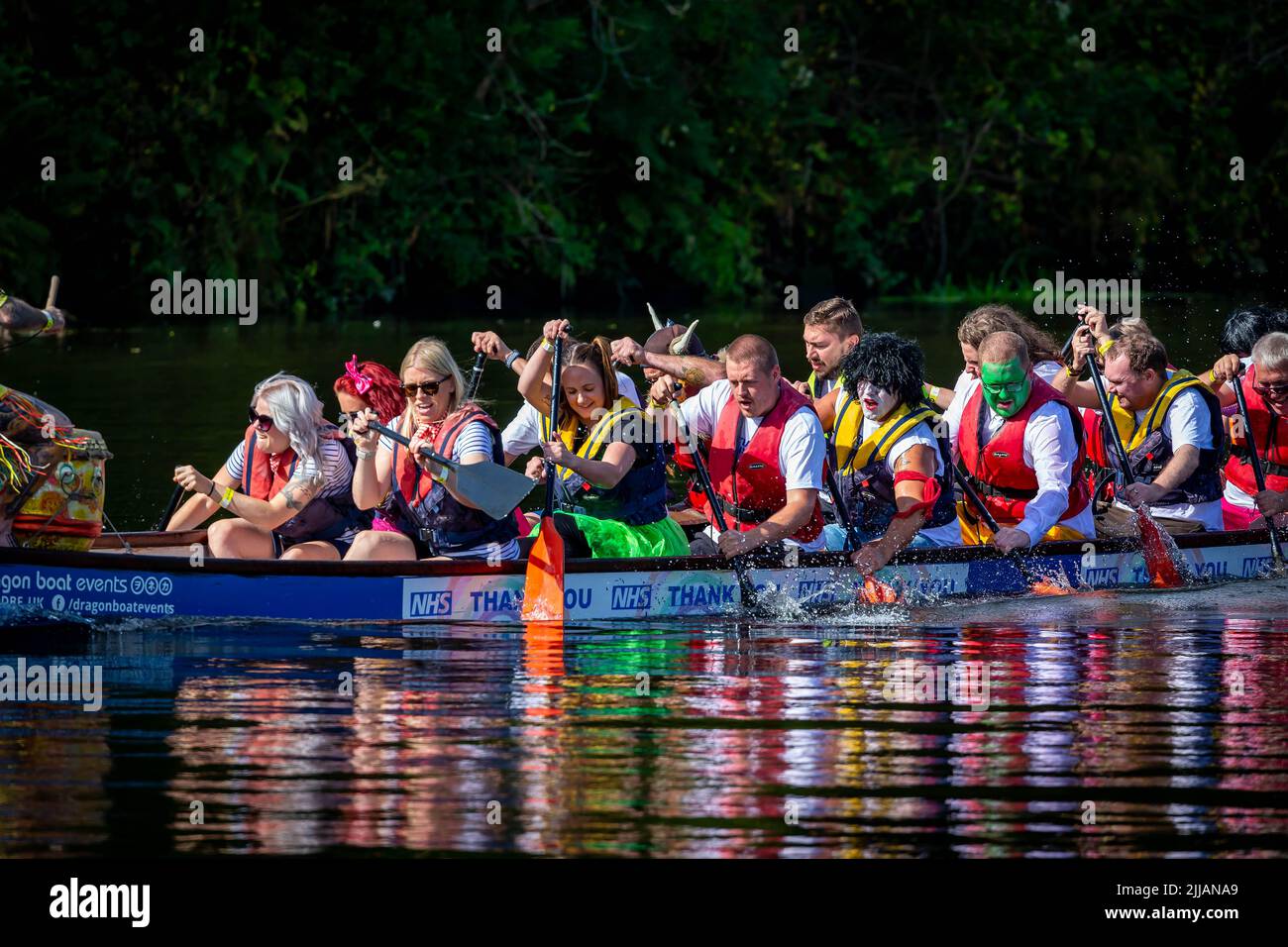 Group of work colleagues, some in fancy dress, paddle their Dragon Boat badly Stock Photo