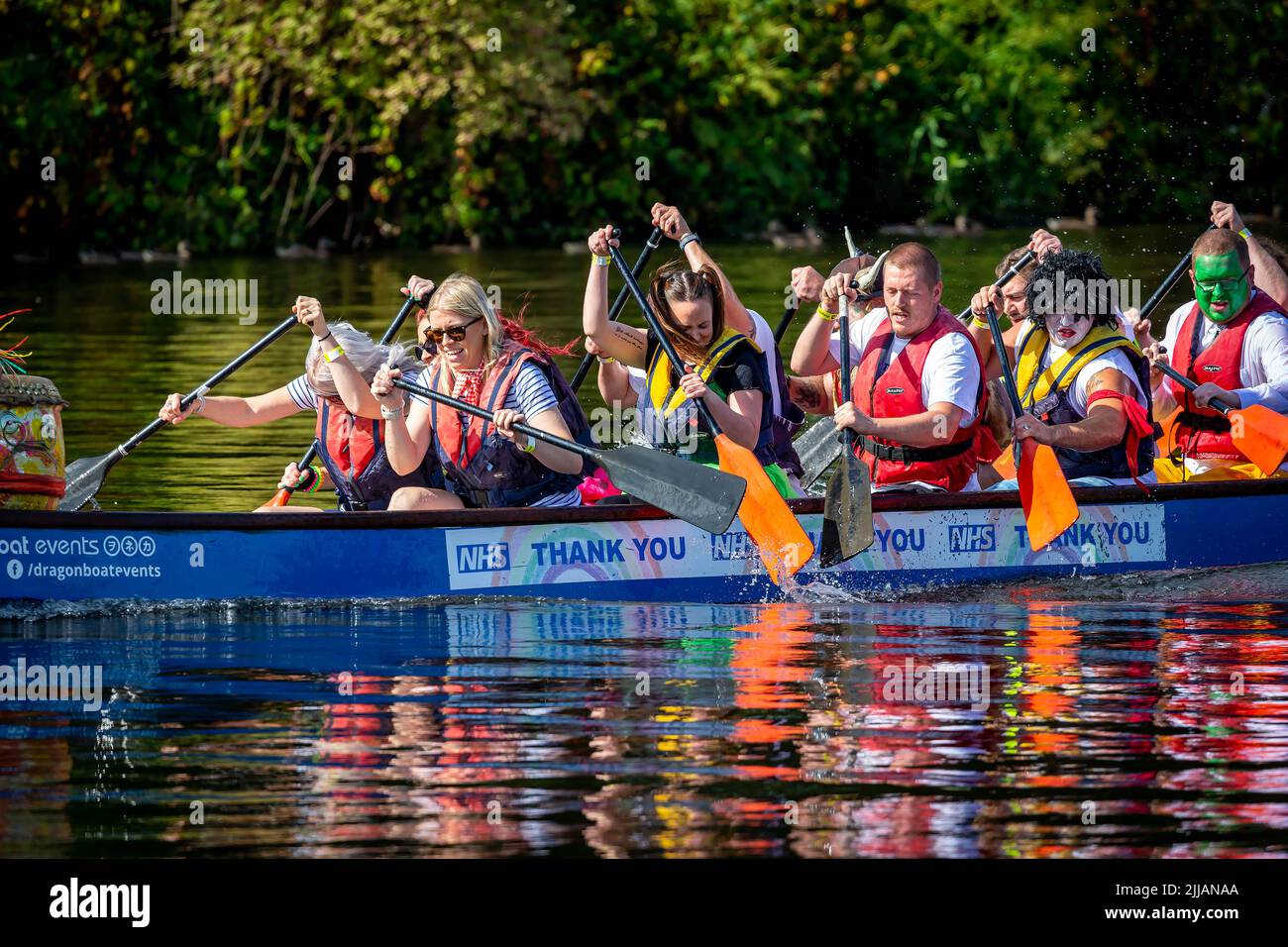 Group of work colleagues, some in fancy dress, paddle their Dragon Boat badly Stock Photo
