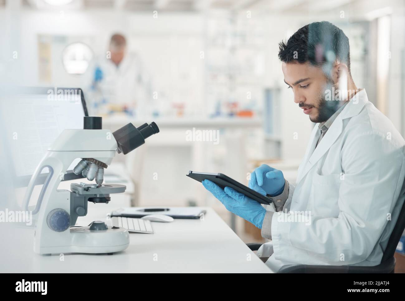 Making informed decisions based off his thorough research. a young scientist using a digital tablet while working in a lab. Stock Photo