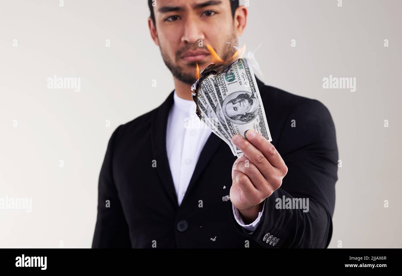 Money is the root to all evil. Studio shot of a young businessman burning a banknote against a white background. Stock Photo