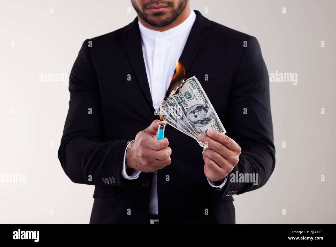 Ive got money to burn. Studio shot of an unrecognisable businessman burning a banknote against a white background. Stock Photo