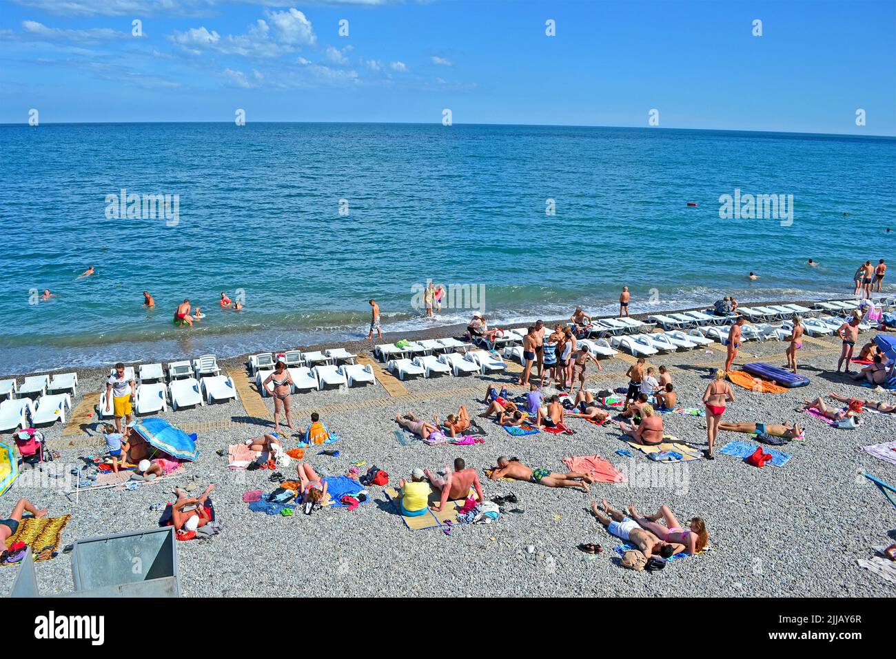 ALUSHTA, UKRAINE: People on the public pebble beach near Black Sea in Alushta, Ukraine. Alushta is famous Crimean resort. Stock Photo