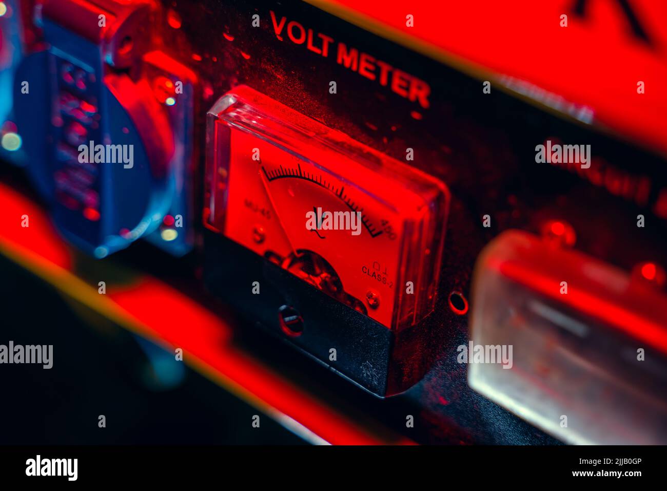 Closeup mechanical voltmeter in red lighting, top view. Voltage