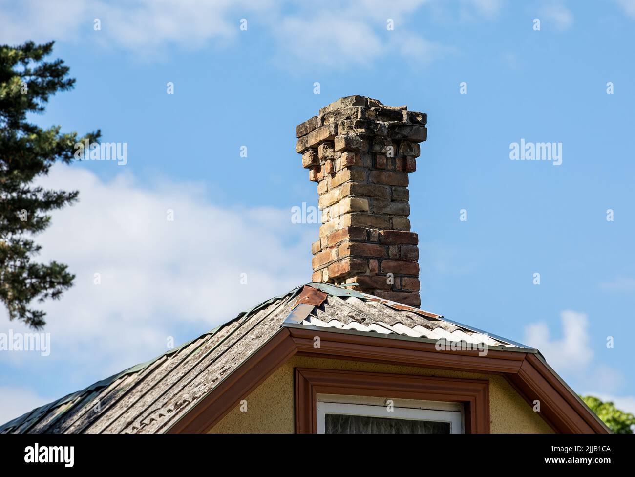 Old brick chimney on the edge of a roof. Heating and fire safety concept.. Stock Photo