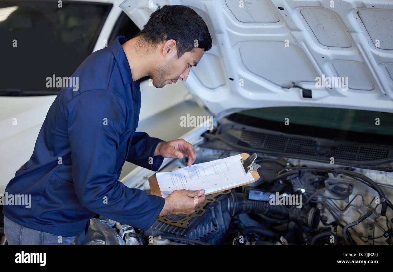 No amount of checks is too many. High angle shot of a handsome young male mechanic working on the engine of a car during a service. Stock Photo