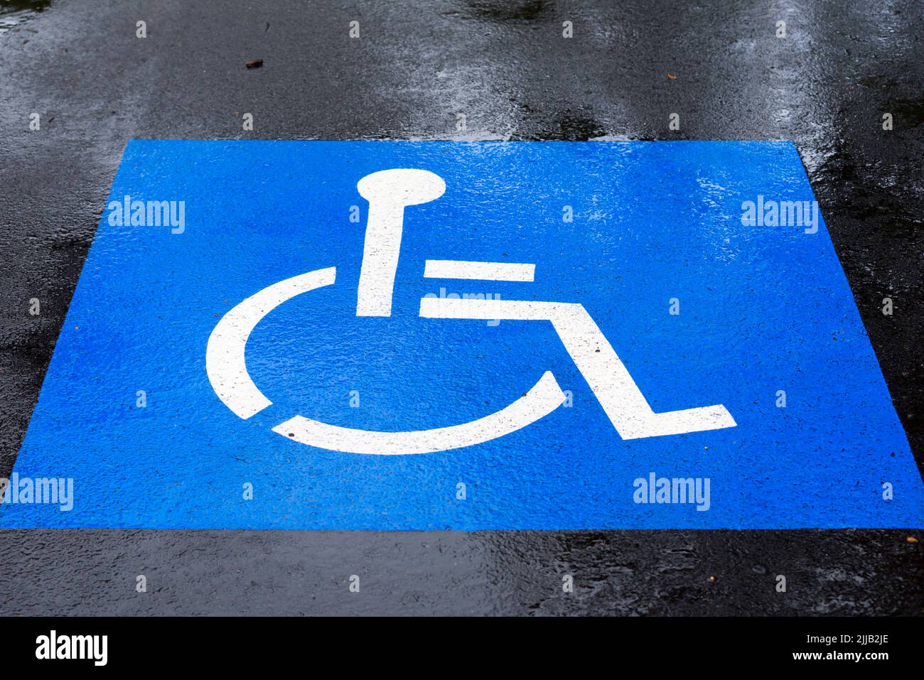 A disabled (wheelchair) access parking symbol painted on a rainy car space at Como Railway Station in Sydney, New South Wales, Australia Stock Photo