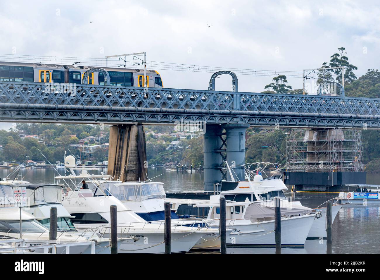 Old Como railway bridge over Georges River, a heritage-listed former railway bridge and now footbridge with the new rail bridge and train at rear. Stock Photo