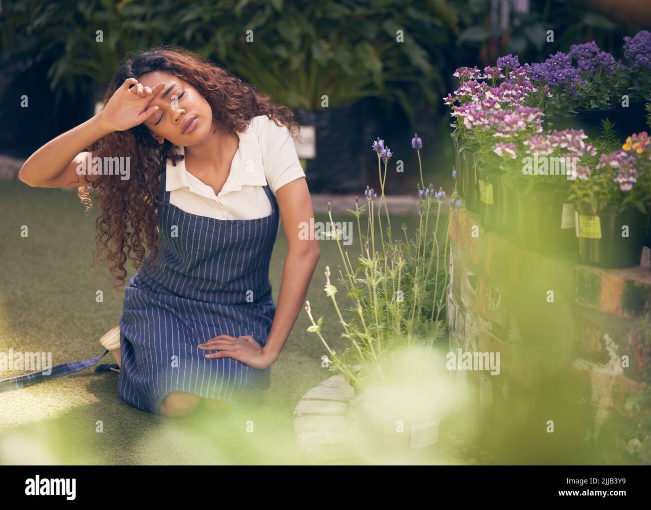 Being a plant mother is tiring. a young florist looking stressed while at work. Stock Photo