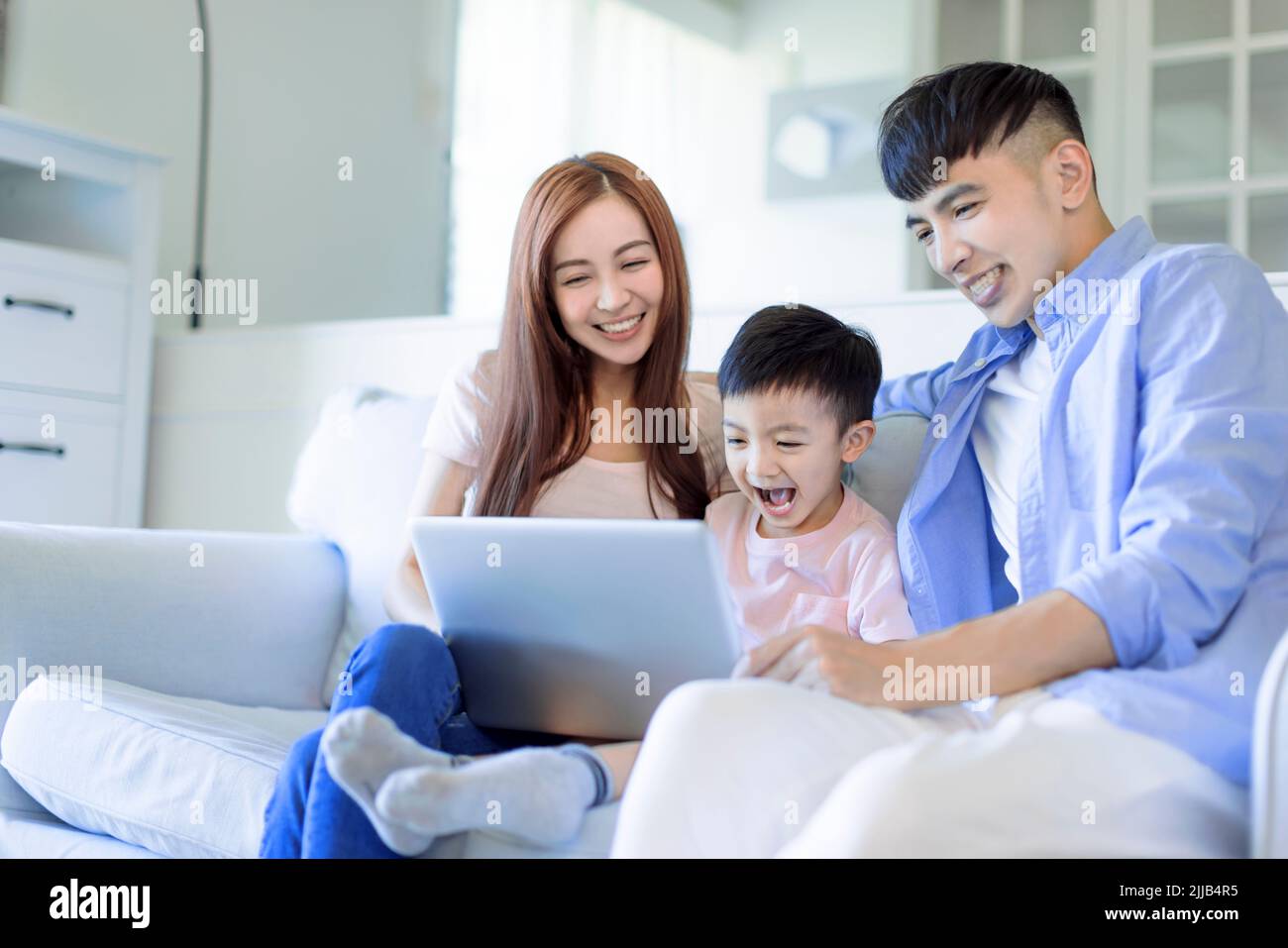 young happy cheerful family  resting on sofa in living room watching the laptop Stock Photo
