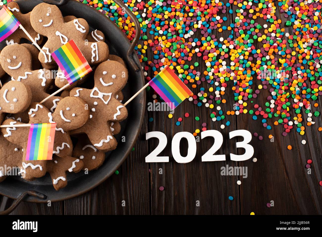 New year background of tray with gingerbread cookie men, rainbow flags and color sprinkles on wooden table Stock Photo