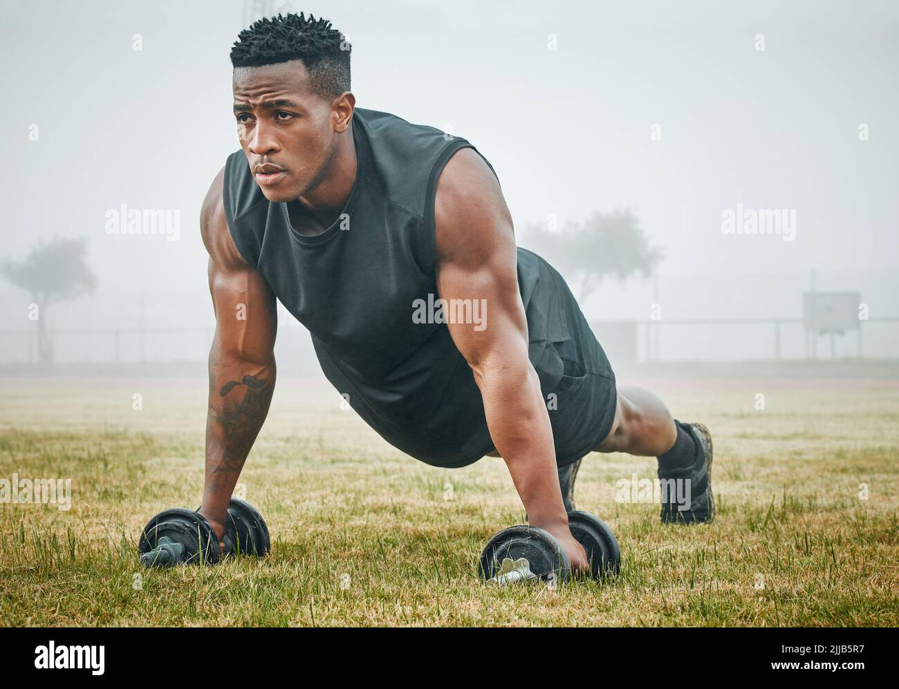 Stay on the rise. a muscular young man exercising with dumbbells ...