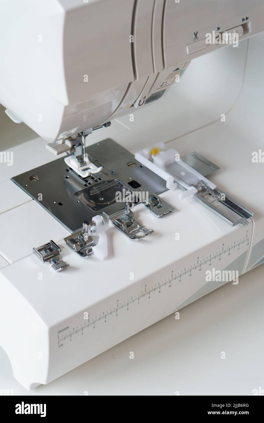 White modern ewing machine and its components close up. Sewing needle plate and replacement