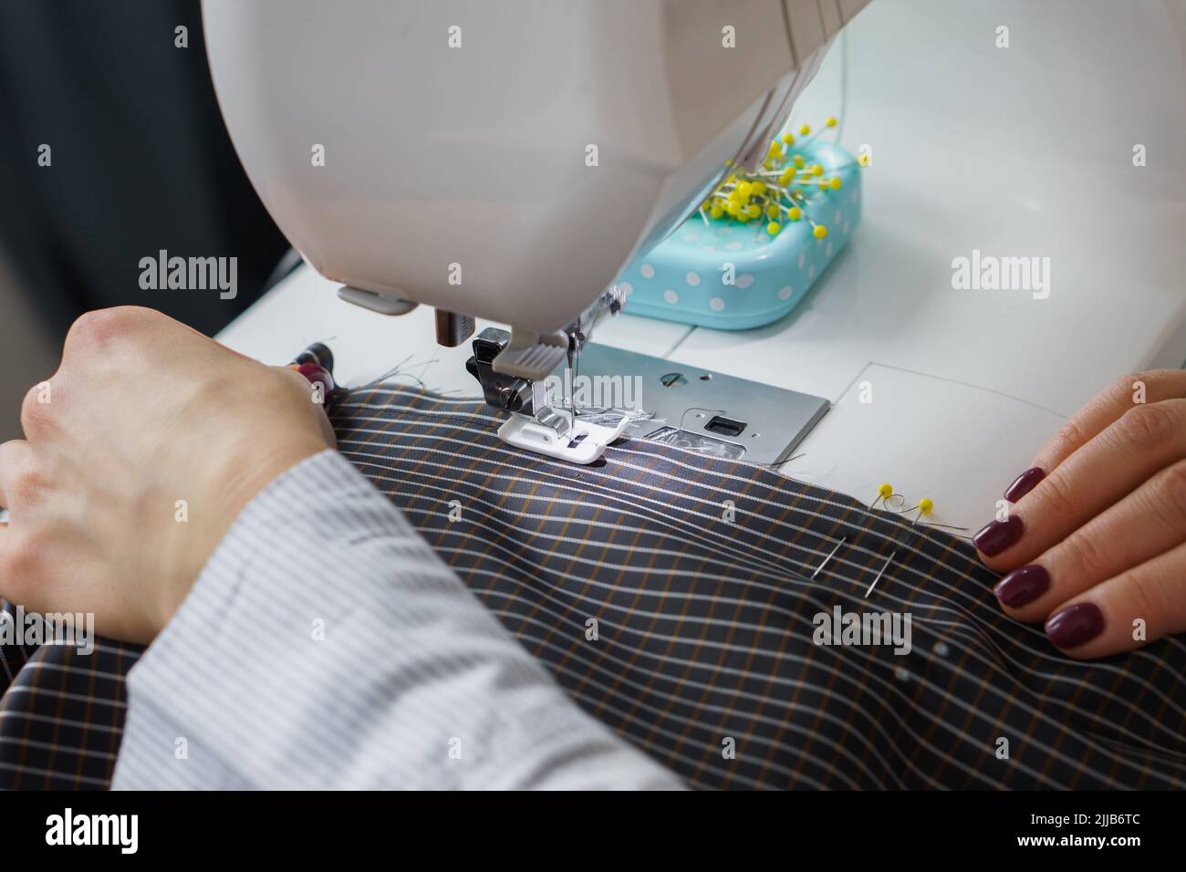 Seamstress woman works on sewing machine. Dressmaker hands work at sewing factory Stock Photo