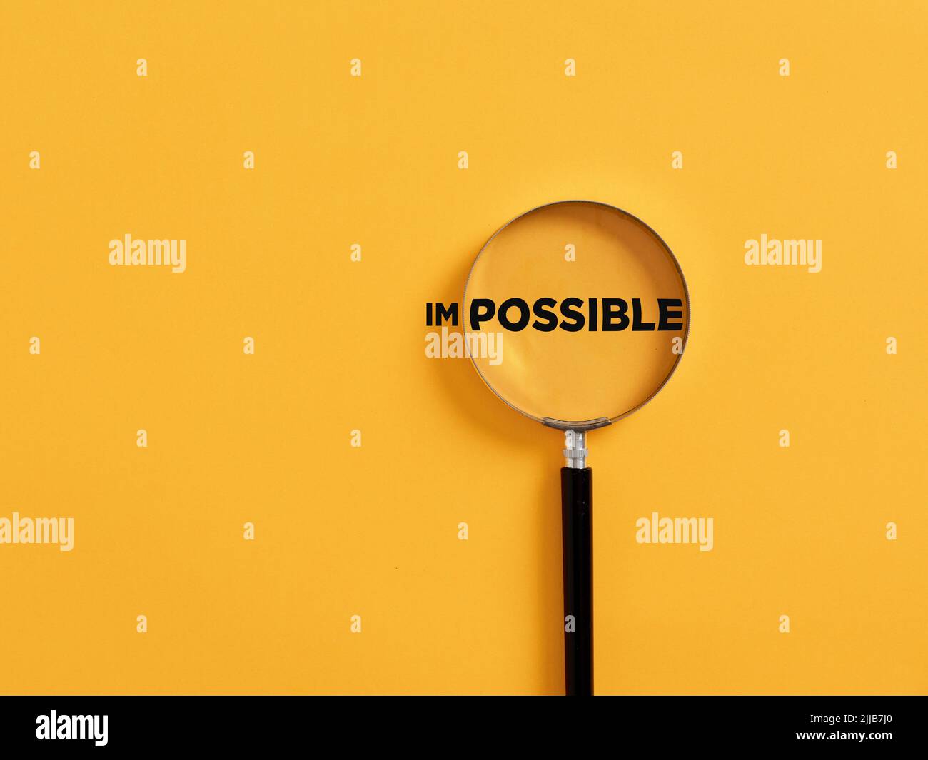 Magnifier focuses on the possible side of the word impossible. It is possible motivational inspirational concept. Stock Photo