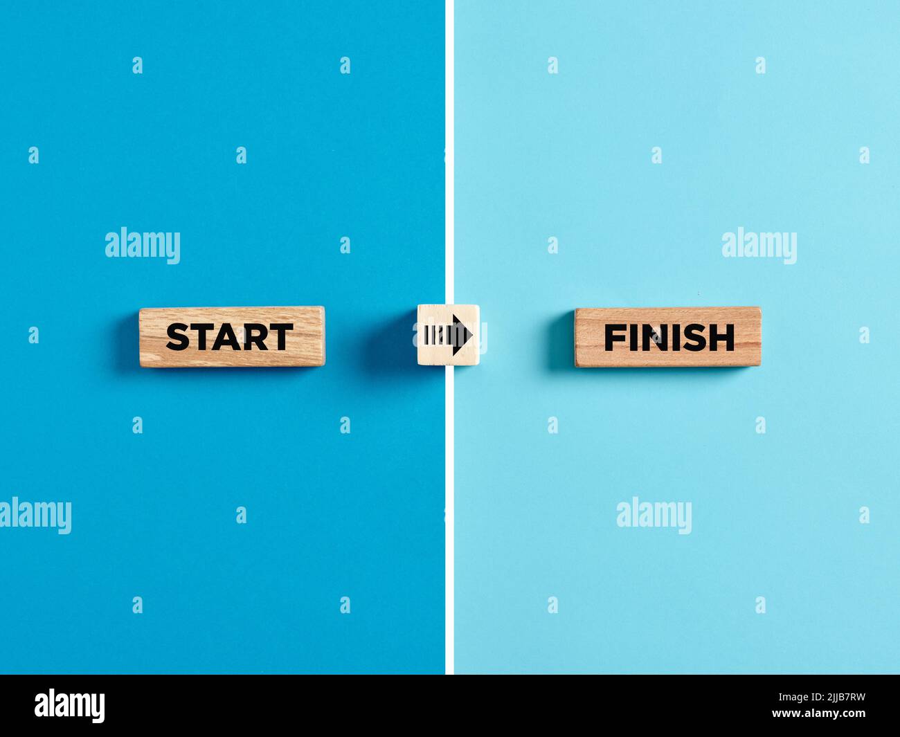 The words start and finish on wooden blocks with arrow direction symbol. Staring and finishing a job, progress or improvement in business concept. Stock Photo