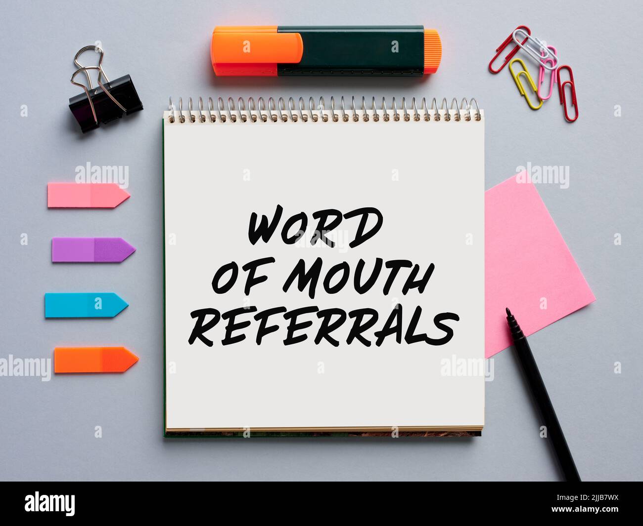 The phrase word of mouth referrals written on a notebook on office desktop. Business marketing concept. Stock Photo