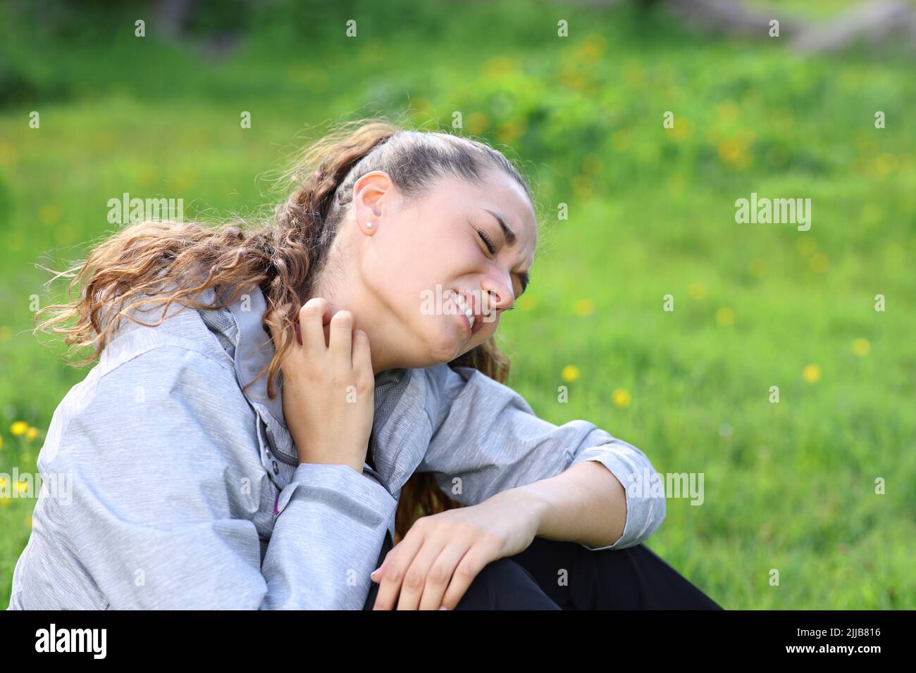 Hiker scratching itchy neck complaining after insect bite in the mountain Stock Photo