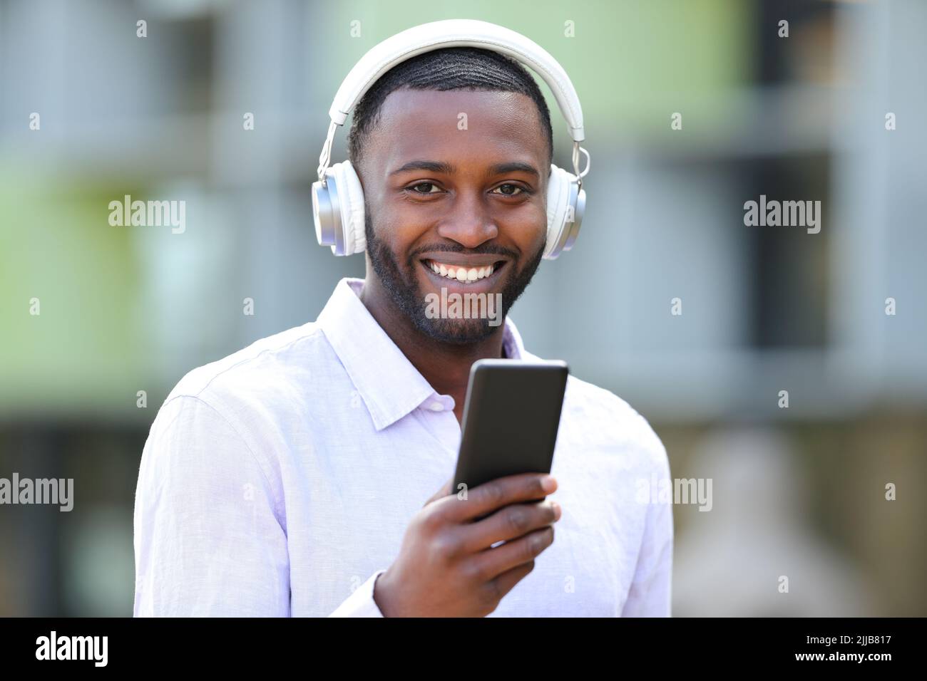 Happy black man listening to music looks at you in the street Stock Photo