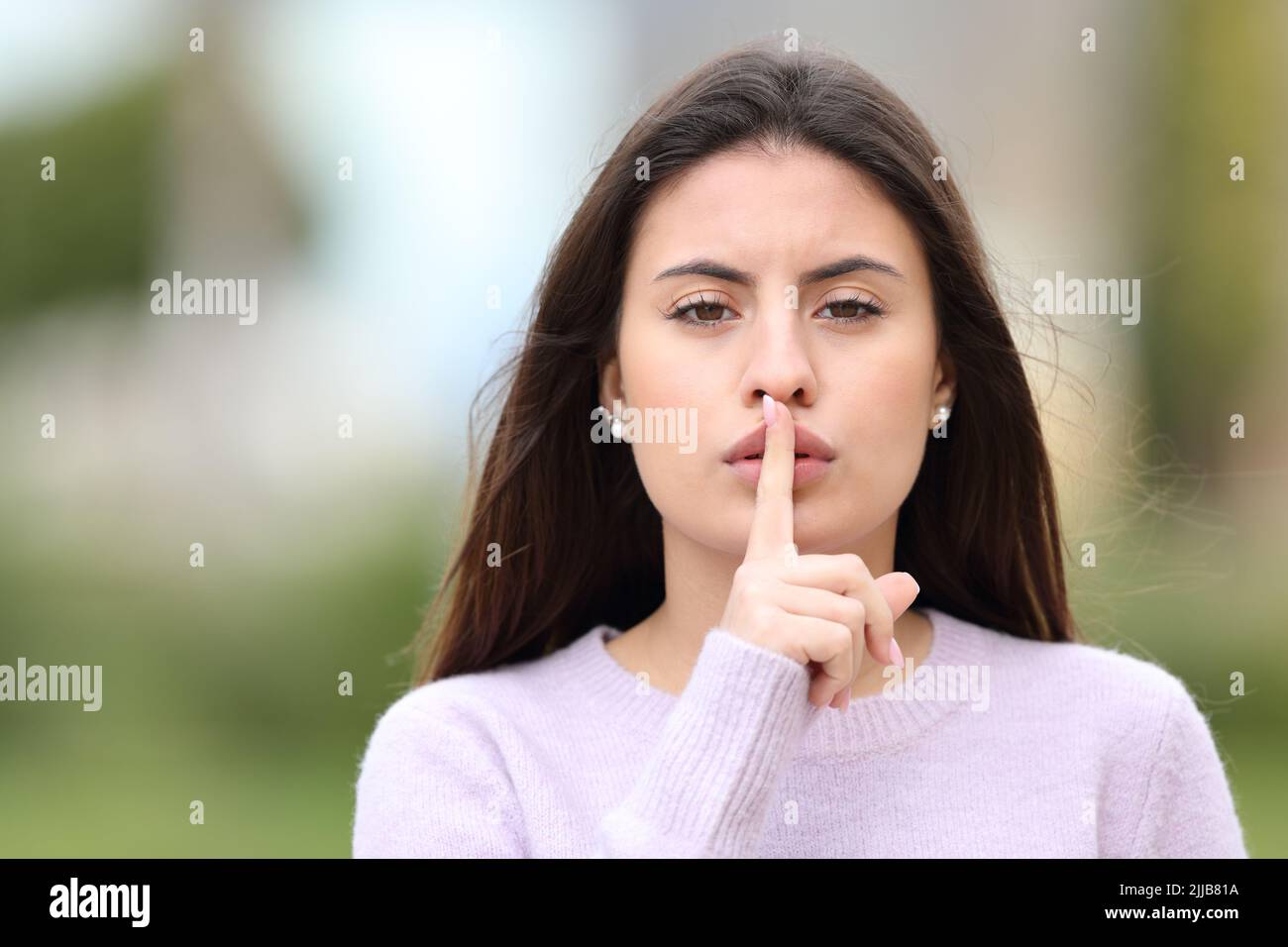 Front view portrait of a serious teen asking for silence in the street Stock Photo