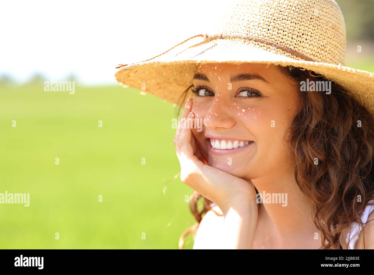 Portrait of a happy beauty woman wearing pamela hat smiling at you with perfect white teeth in a field a suny day Stock Photo