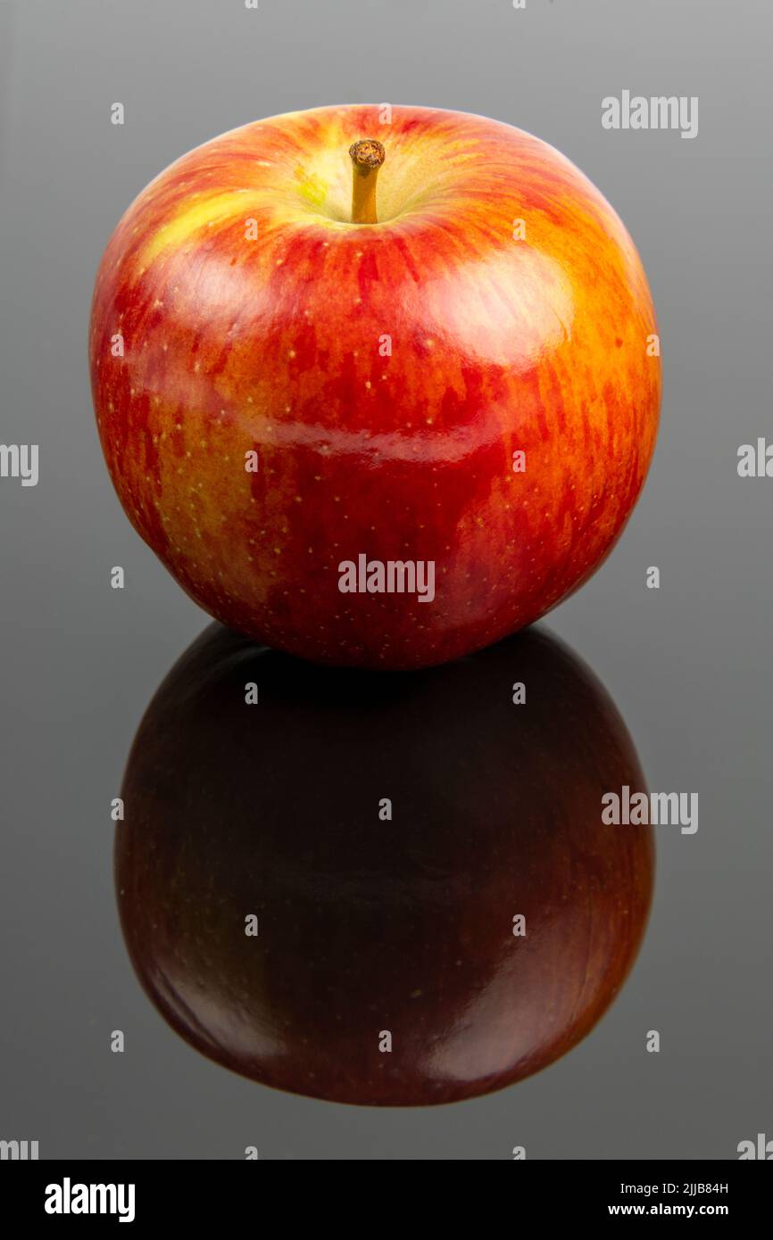 Braeburn apple on a dark reflective surface Stock Photo