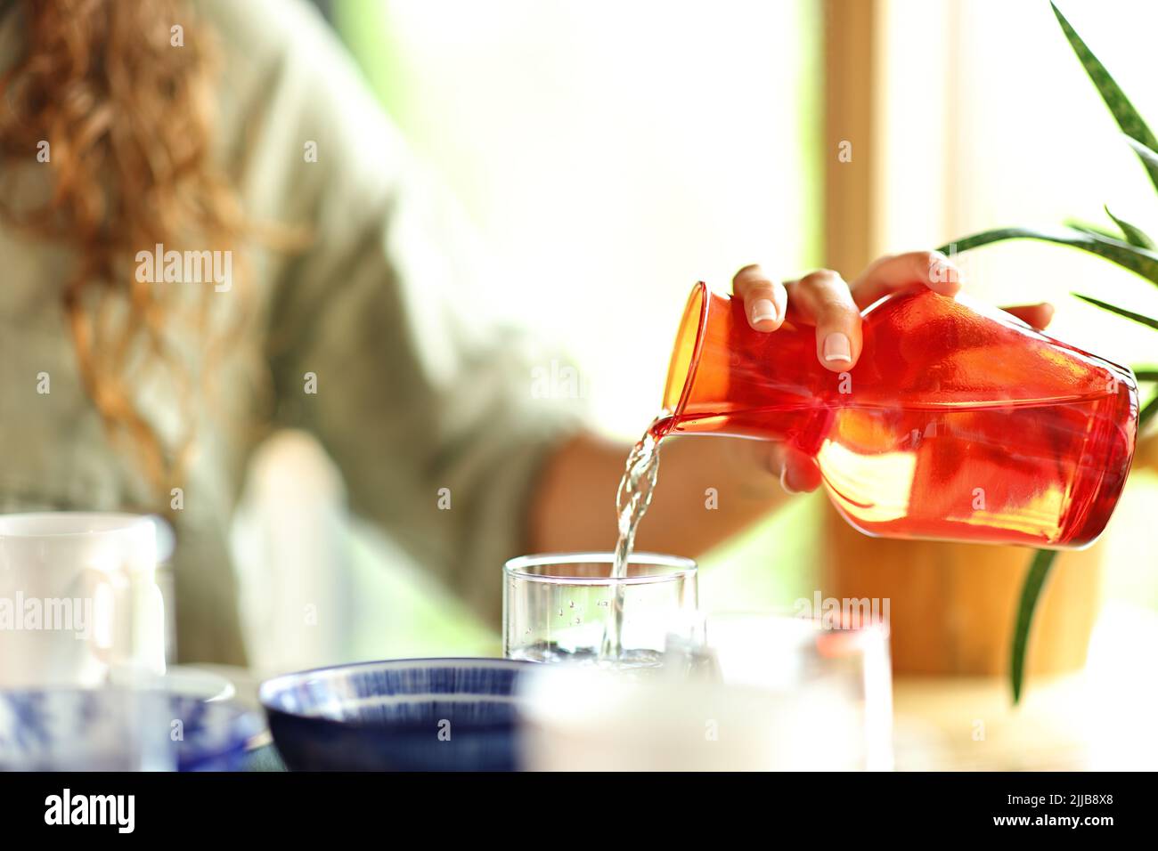 Close up portrait of a woman hand pouring water into a glass in a restaurant Stock Photo