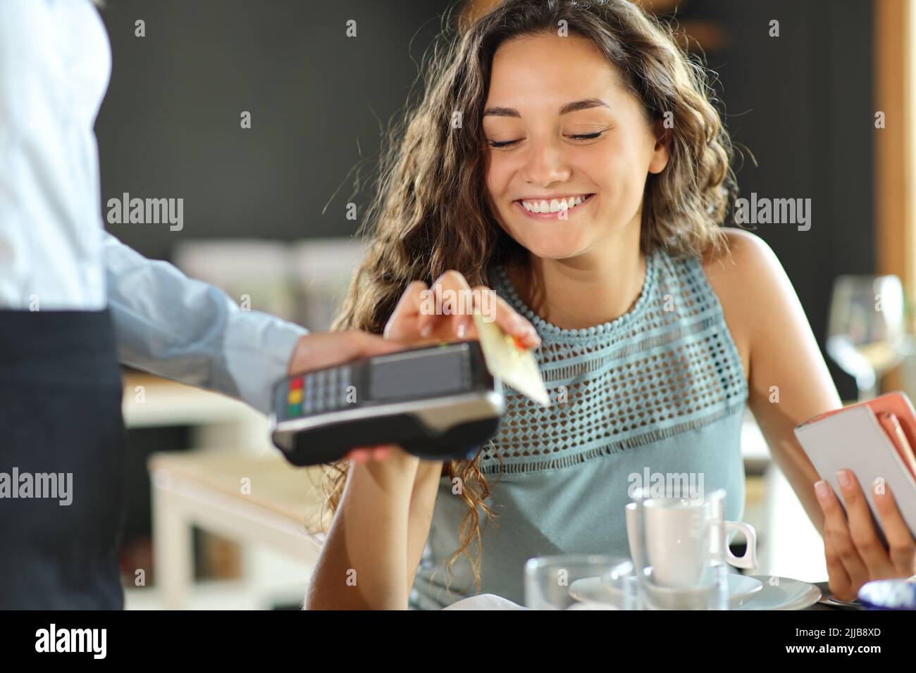 Happy woman paying lunch in a restaurant with credit card Stock Photo
