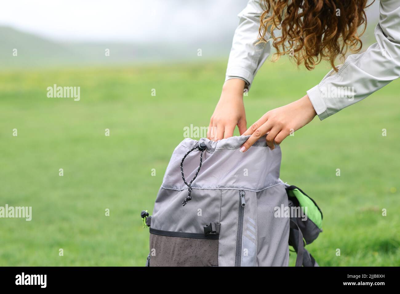 Close up portrait of a hiker searching inside of a backpack in the mountain Stock Photo