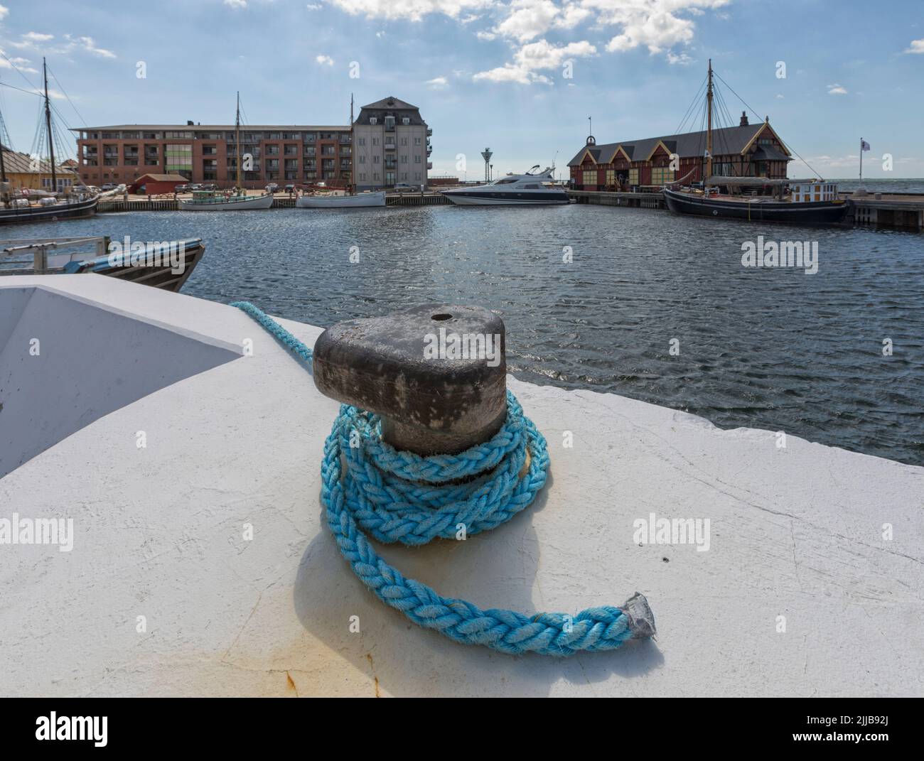 Harbor of Rudkøbing, Langeland, Denmark, with historic warehouse, old and new vessels. Mooring bollard in foeground. Stock Photo