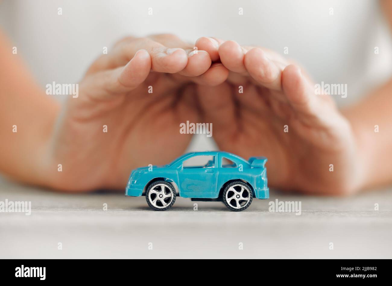 Take care of your car. a unrecognizable female covering a toy car with