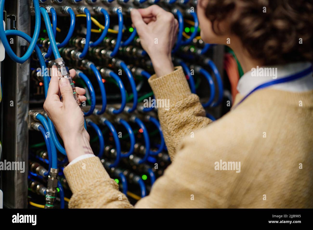 Close-up of young female engineer connecting wires in server cabinet ...