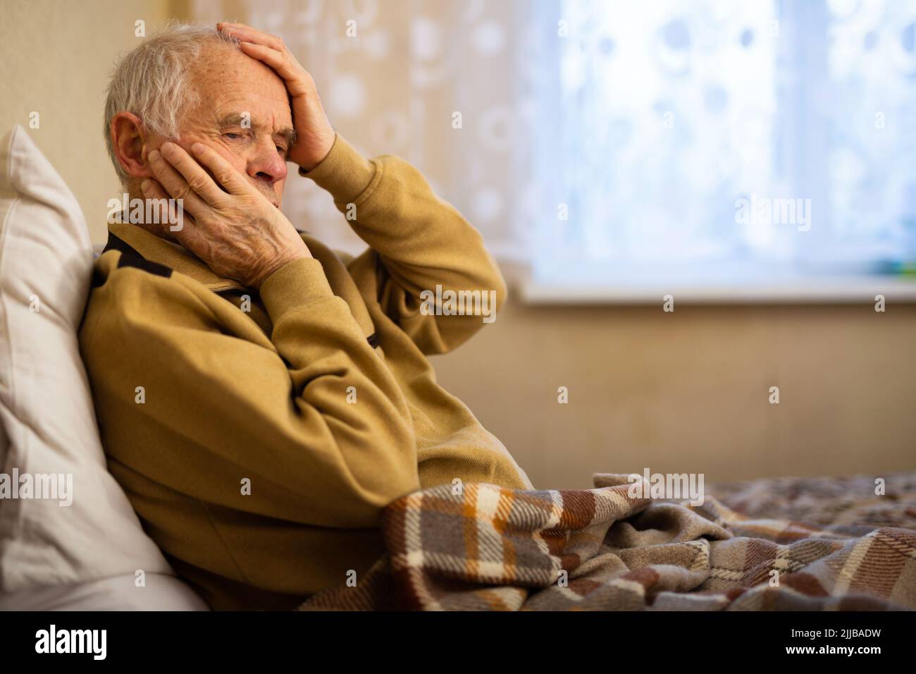 gray haired elderly man agonizing headache at home Stock Photo