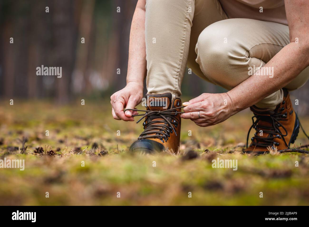 Woman tying shoelace on her hiking boot. Tourist is getting ready for