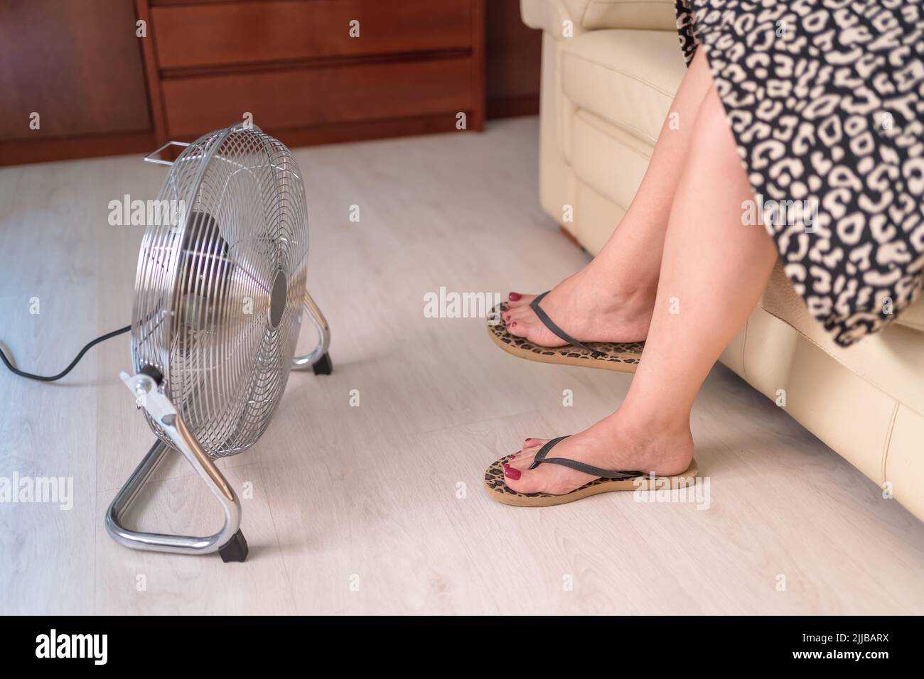 Fan giving fresh air on the feet of a woman because of the high heat it ...