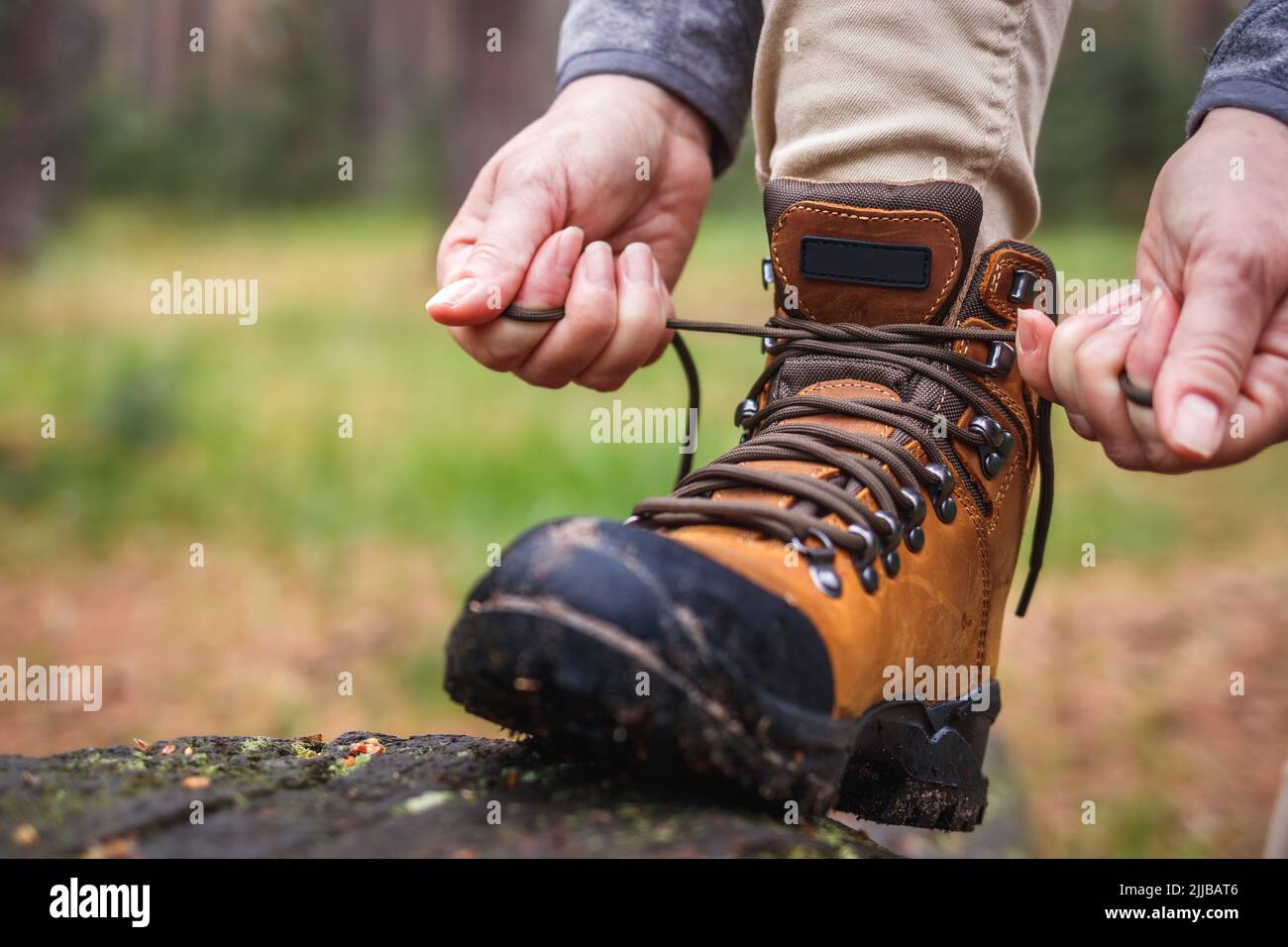Woman tying shoelace on her hiking boot. Tourist is getting ready for