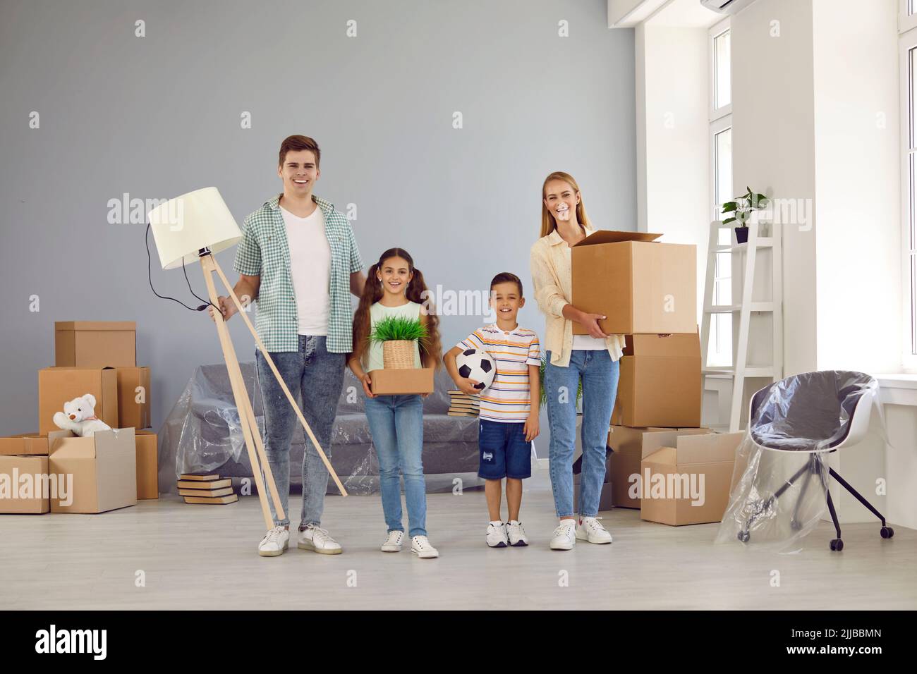 Portrait of happy parents and children with their things in their hands in their new apartment. Stock Photo