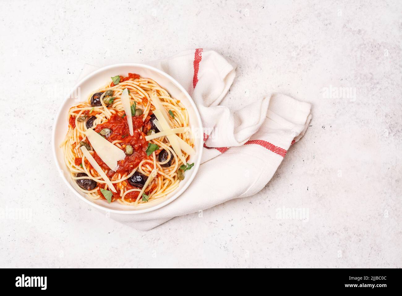 Spaghetti alla puttanesca . Italian pasta with tomatoes, olives, capers, anchovies and parsley. Italian food. Copy space. Top view Stock Photo