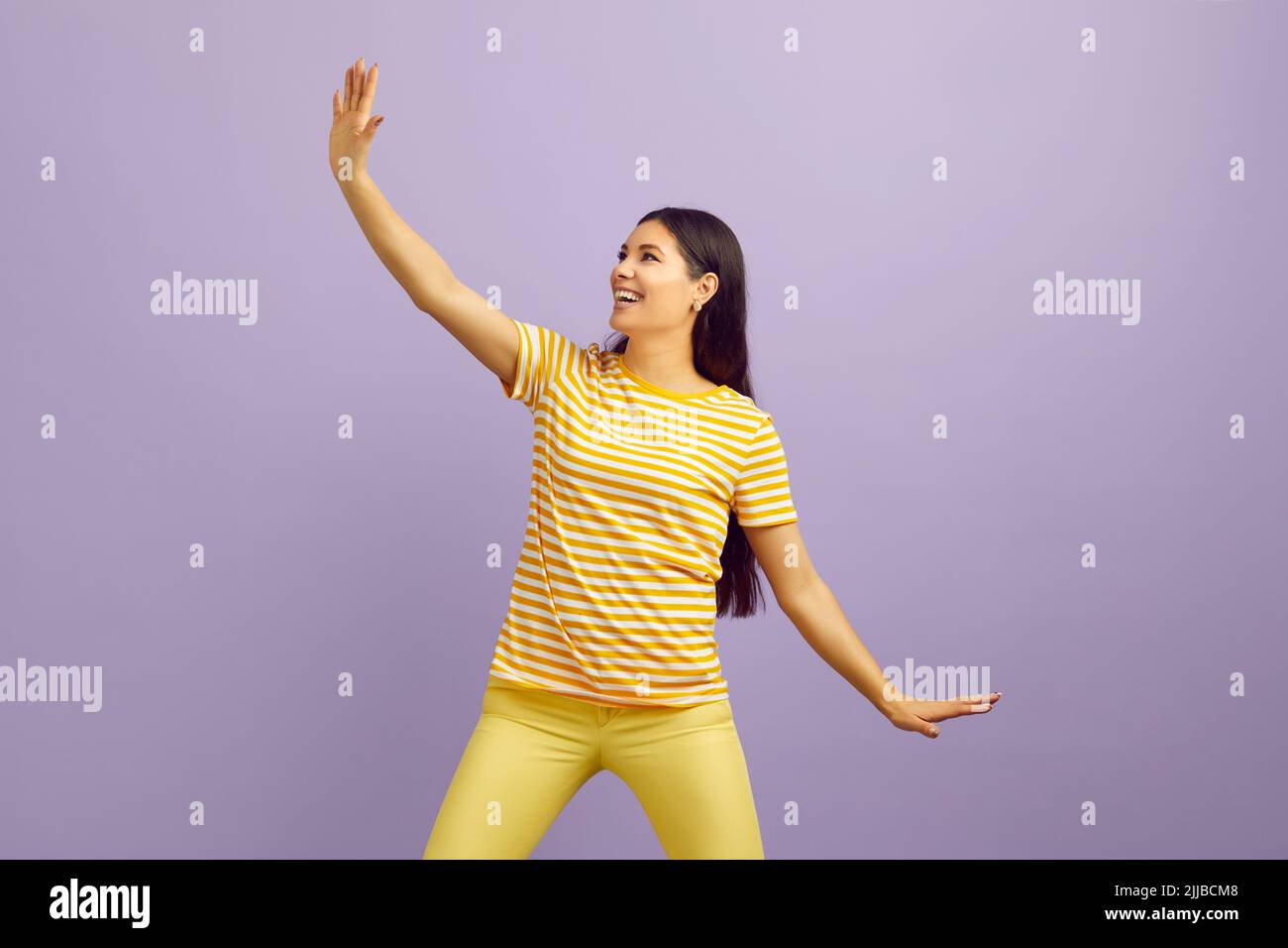 Funny crazy woman having fun showing funny movements on pastel purple background. Stock Photo