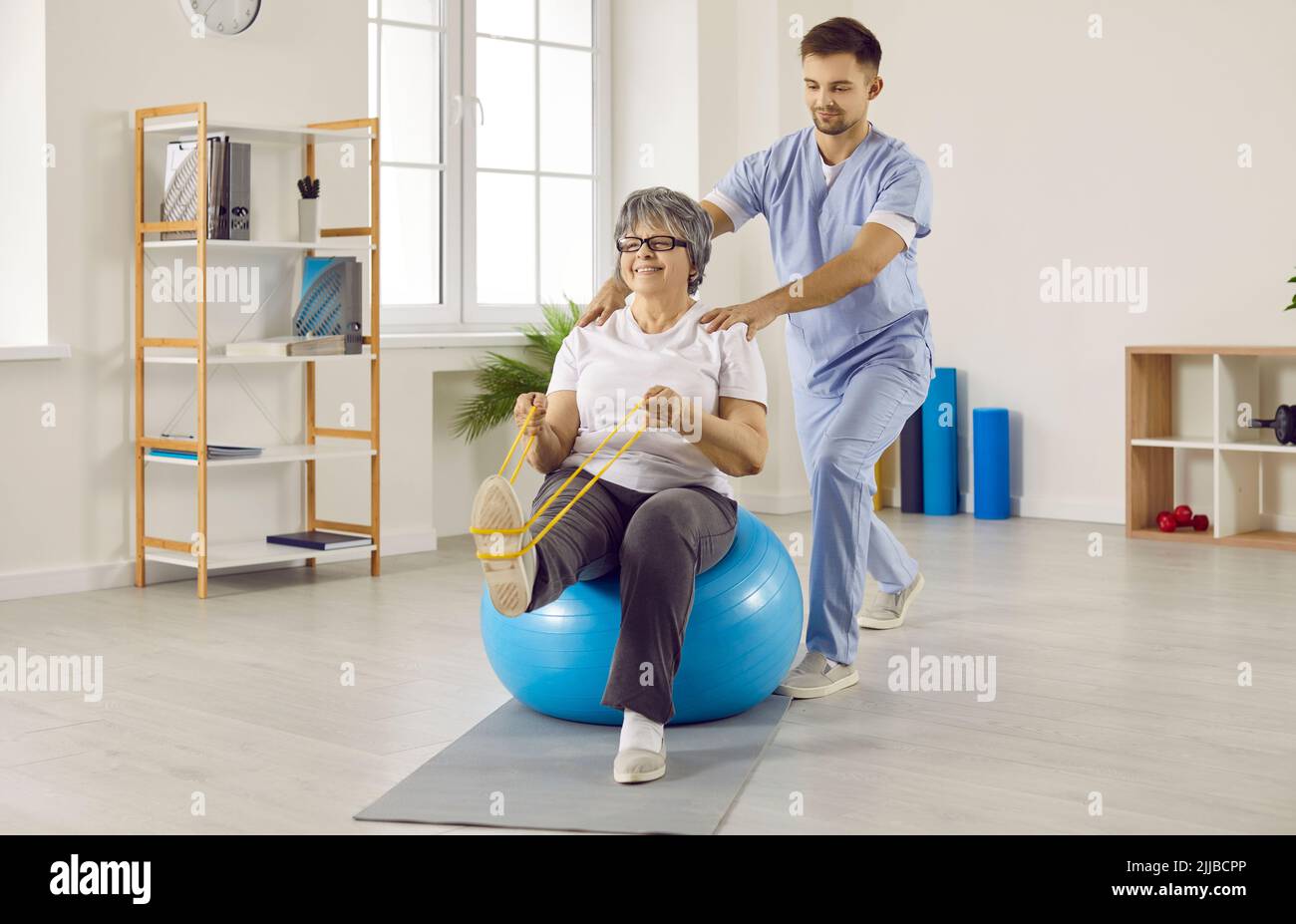 Professional male physiotherapist works with senior female patient in rehabilitation center. Stock Photo