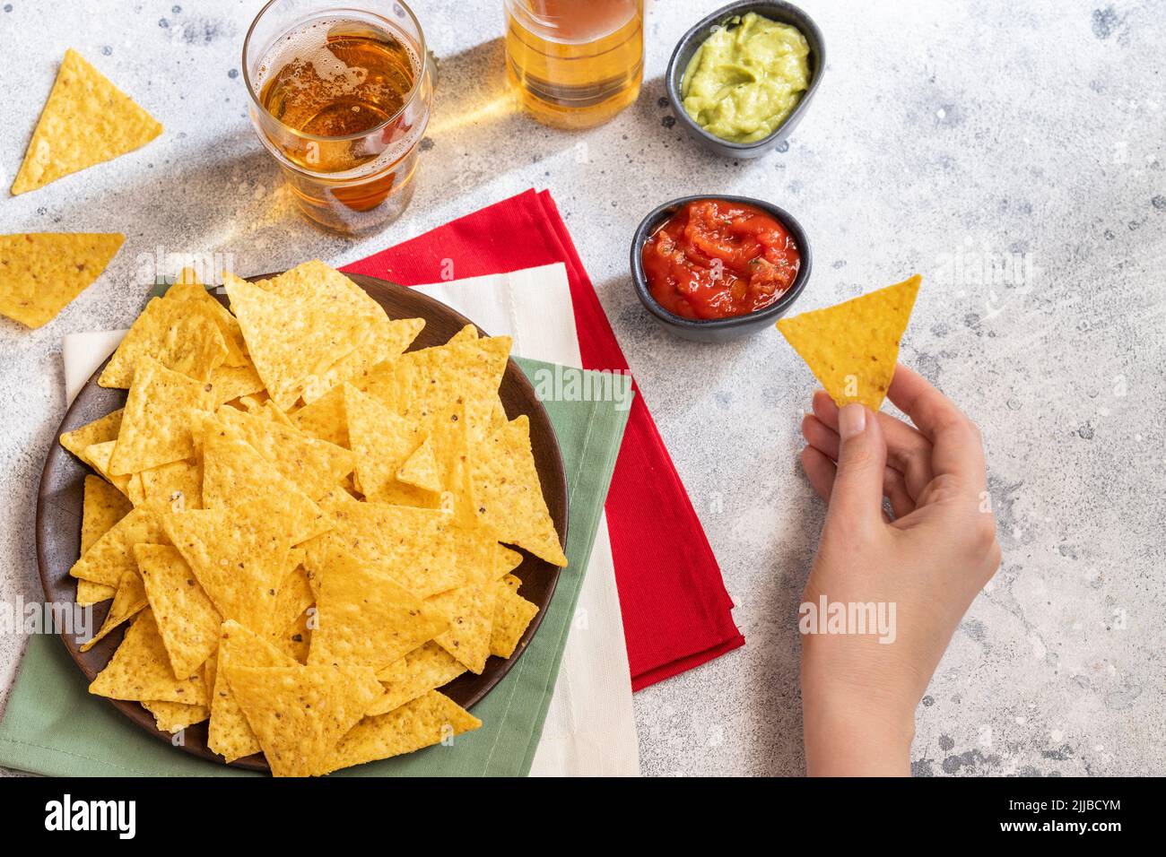 Female hand hold one of nachos, Mexican snack served with traditional