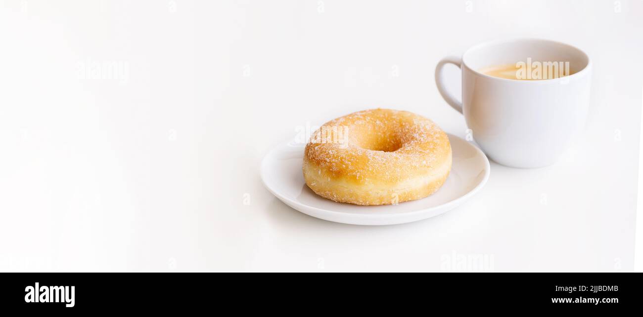 Cup of coffee with classic sugar donut on white background for banner with copy space.Good morning and breakfast concept Stock Photo
