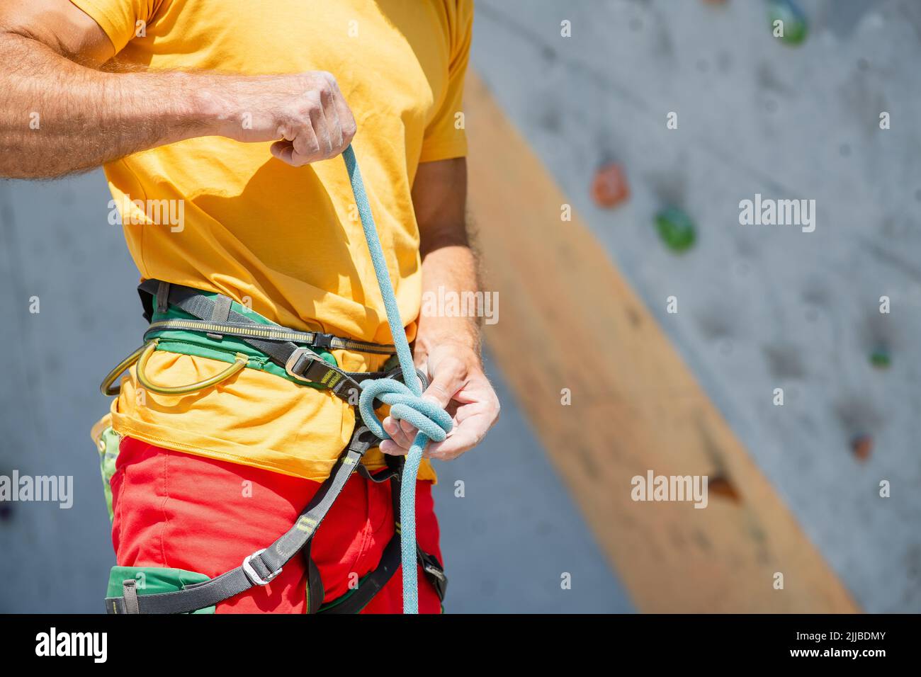 A climber knits a knot. A man prepares to climb a climbing route. Insurance and safety in rock
