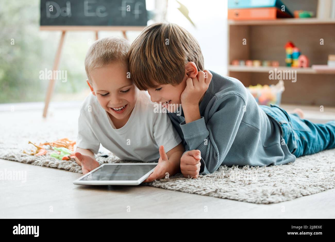 Family faces are magic mirrors. two brothers using a tablet at home Stock Photo Alamy