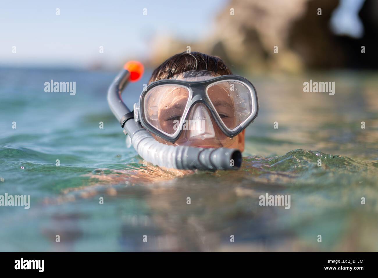 Boy with goggles and pipe before diving at rocky seashore portrait Stock Photo
