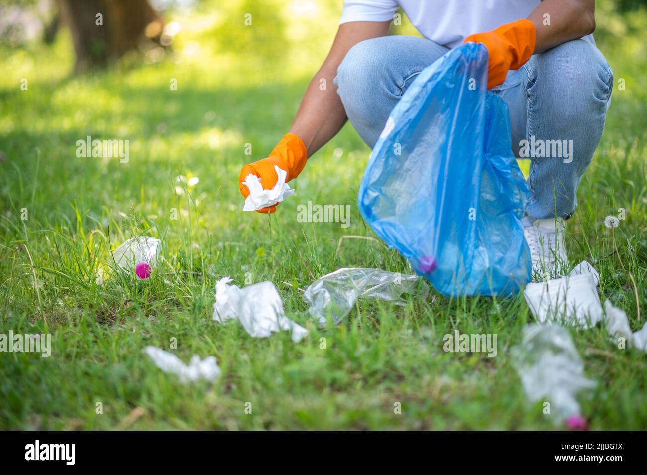 Man crouched picking up trash in park Stock Photo