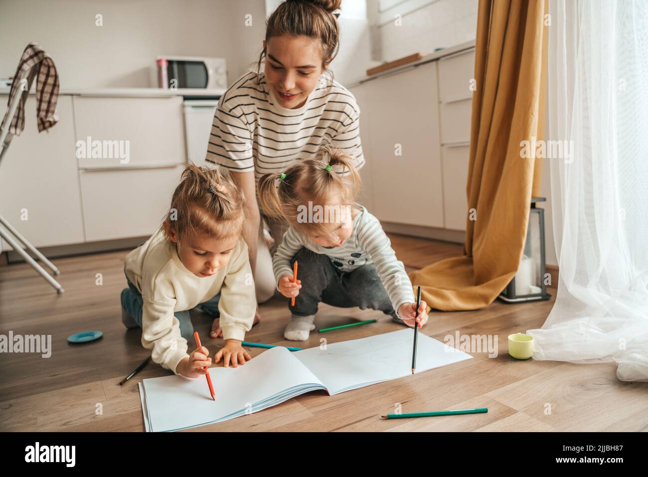 Woman sitting on the kitchen floor with her creative children Stock Photo