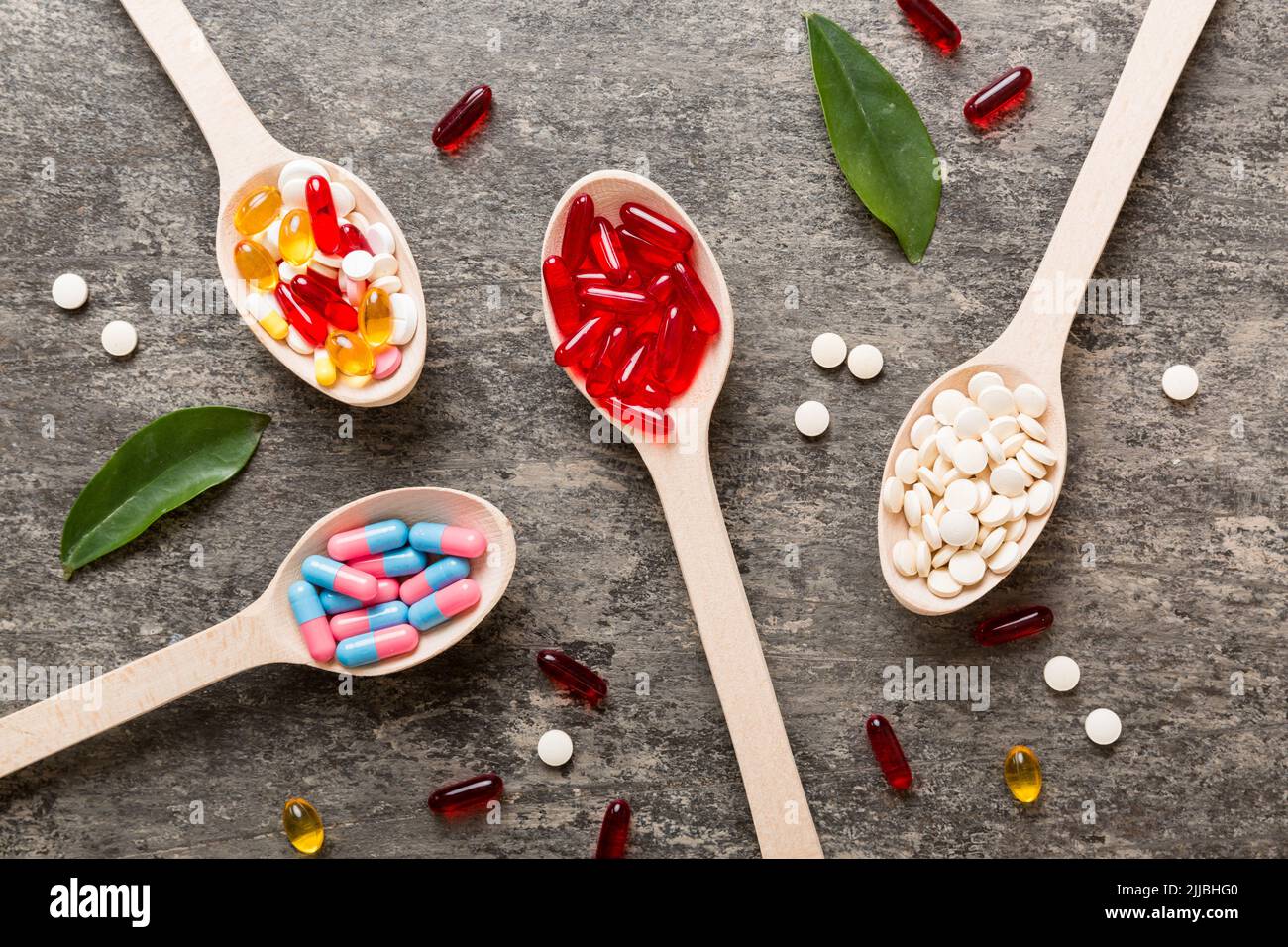 Vitamin capsules in a spoon on a colored background. Pills served as a healthy meal. Red soft